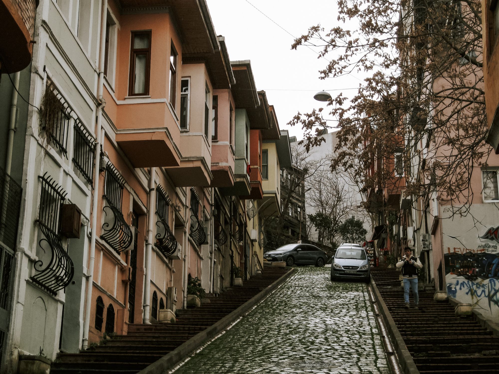 Charming cobblestone street with colorful houses and cars on a steep incline in Istanbul, Turkey