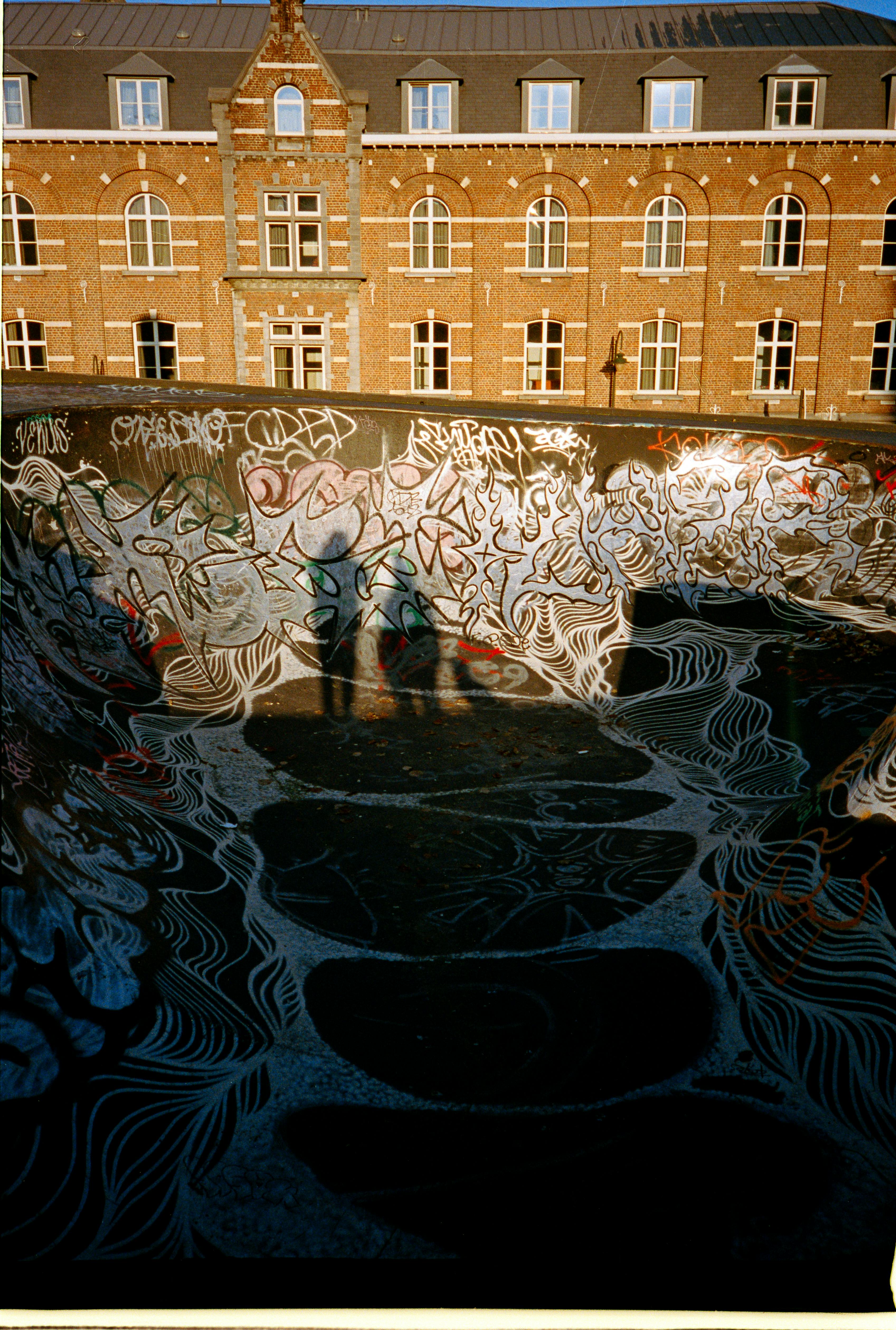 Captivating urban skatepark scene with vibrant graffiti and people's shadows on a sunny day.