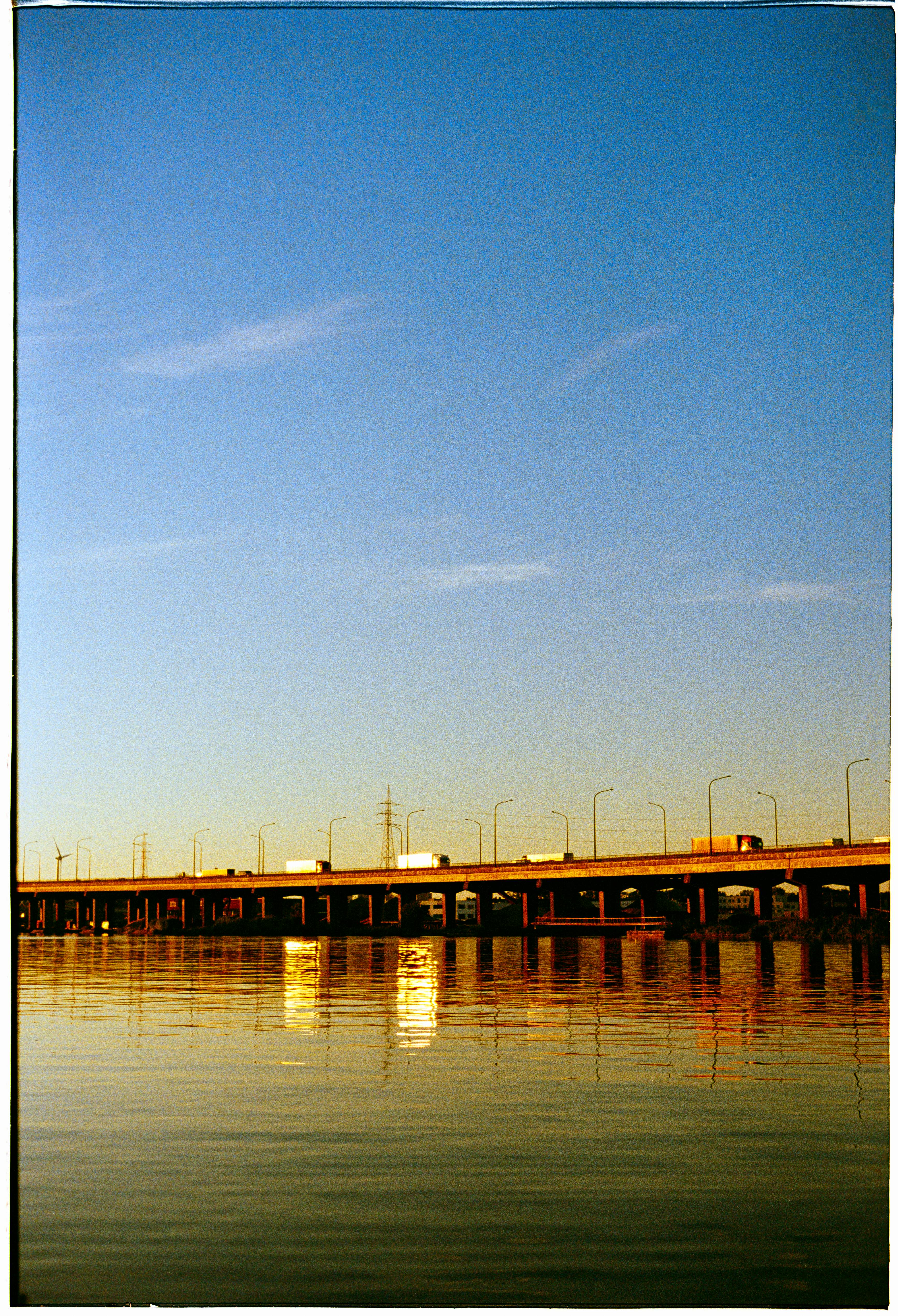 A stunning view of a bridge over calm river waters under a clear sky during sunset.