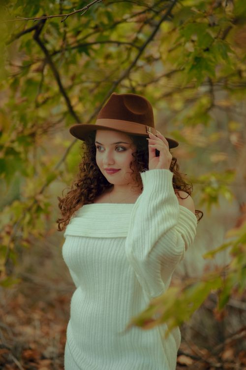 Free Portrait of a fashionable woman in a white sweater and hat in an autumn forest. Stock Photo
