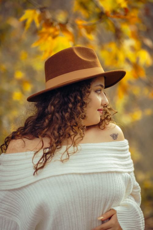 Free Stylish woman with curly hair in a hat captured in a fall setting. Stock Photo