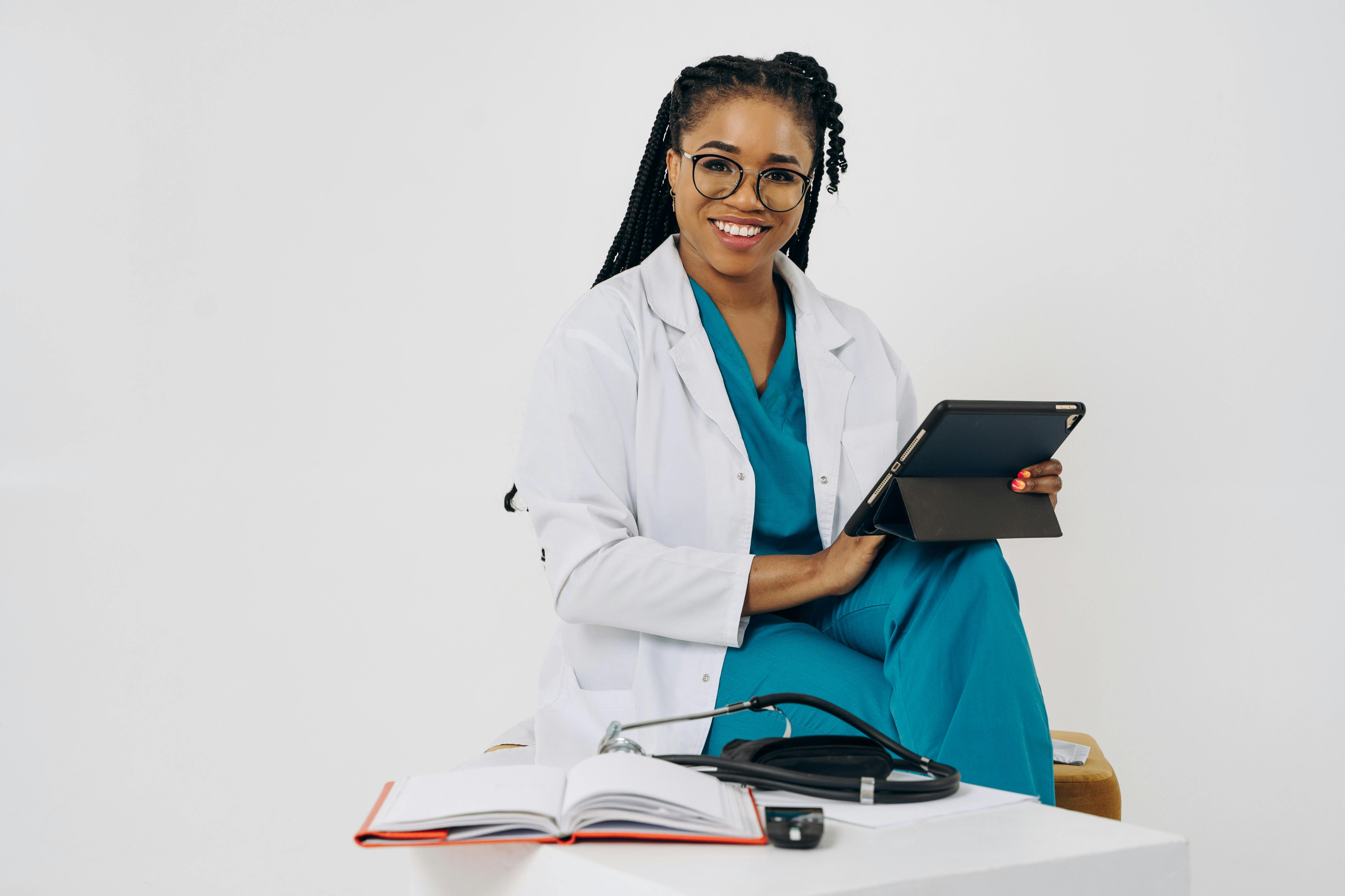 Smiling female doctor with a tablet and stethoscope in a bright office setting.
