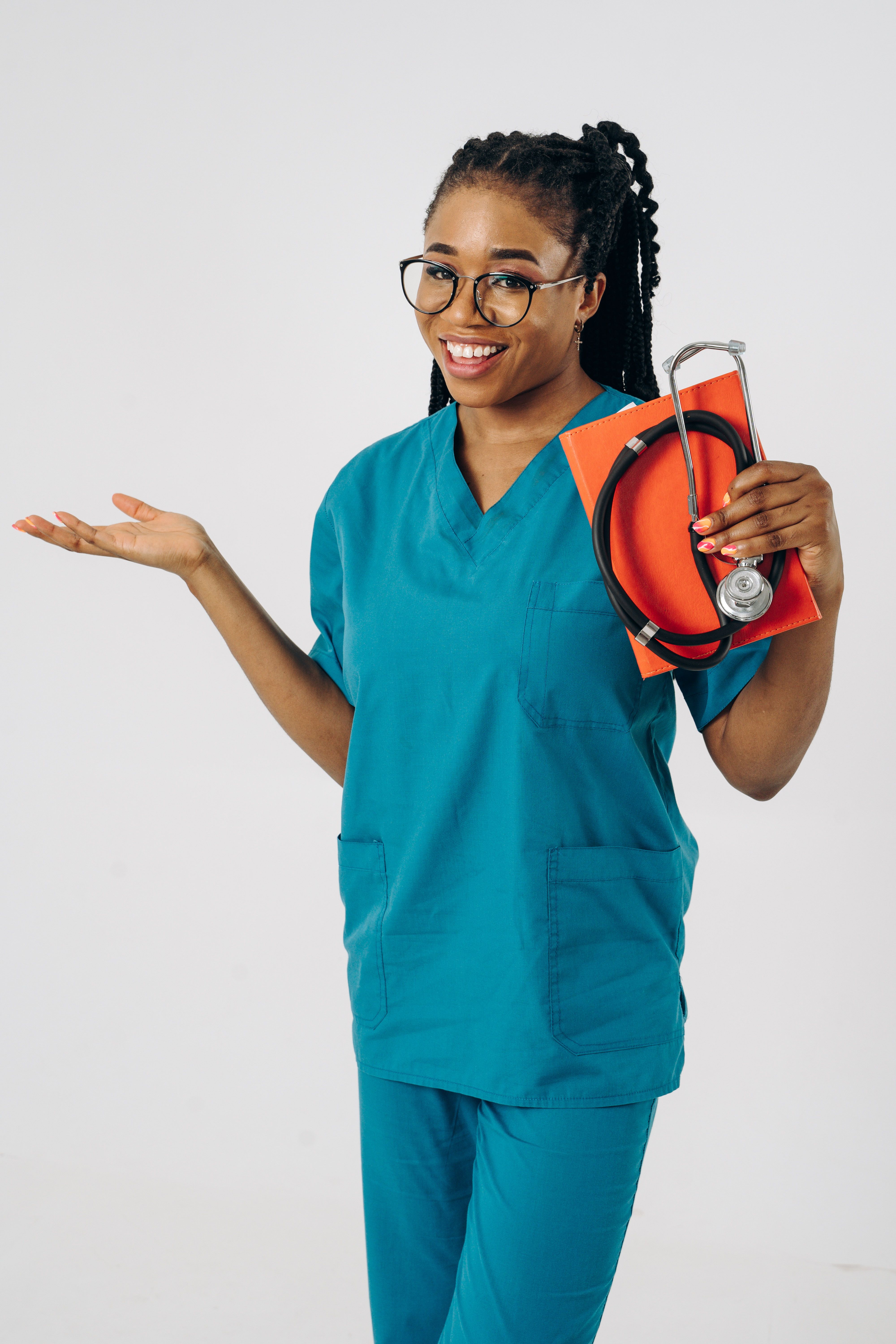 Confident female doctor smiling and gesturing with stethoscope in hand against a white background.
