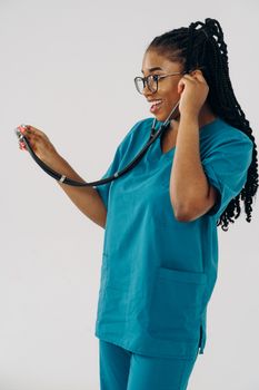 Confident black nurse smiling with a stethoscope against a white background.