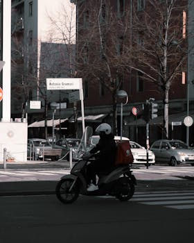 A motor scooter delivery driver on city streets, captured in an Italian urban setting.