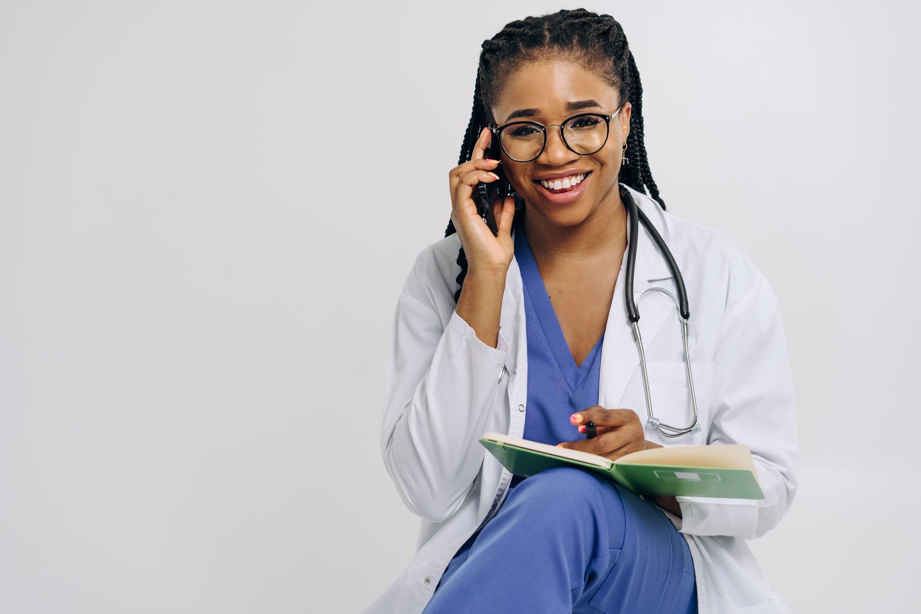 Smiling doctor using a phone while holding notes in a modern practice office