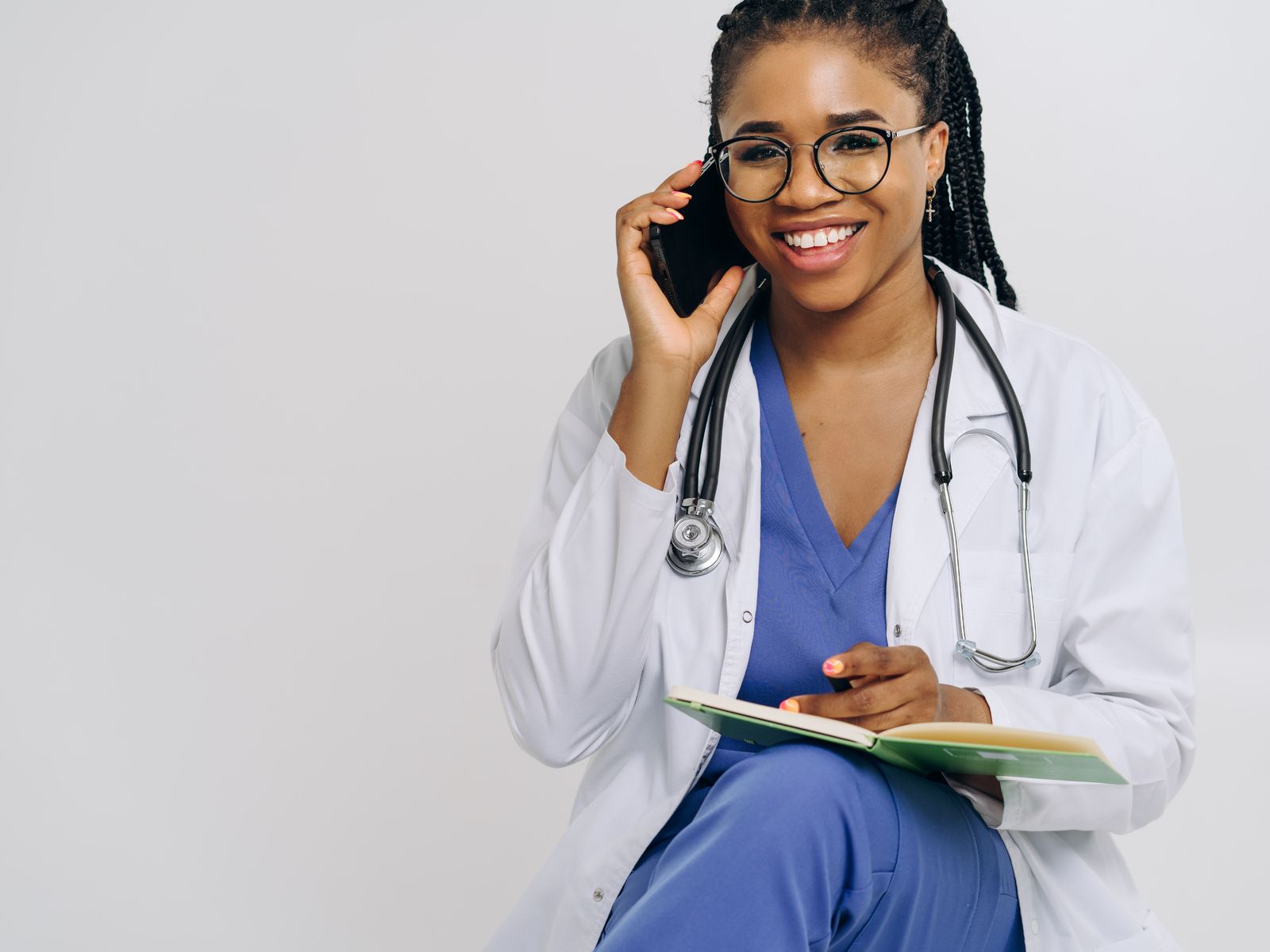 Smiling doctor speaking on a phone while taking notes