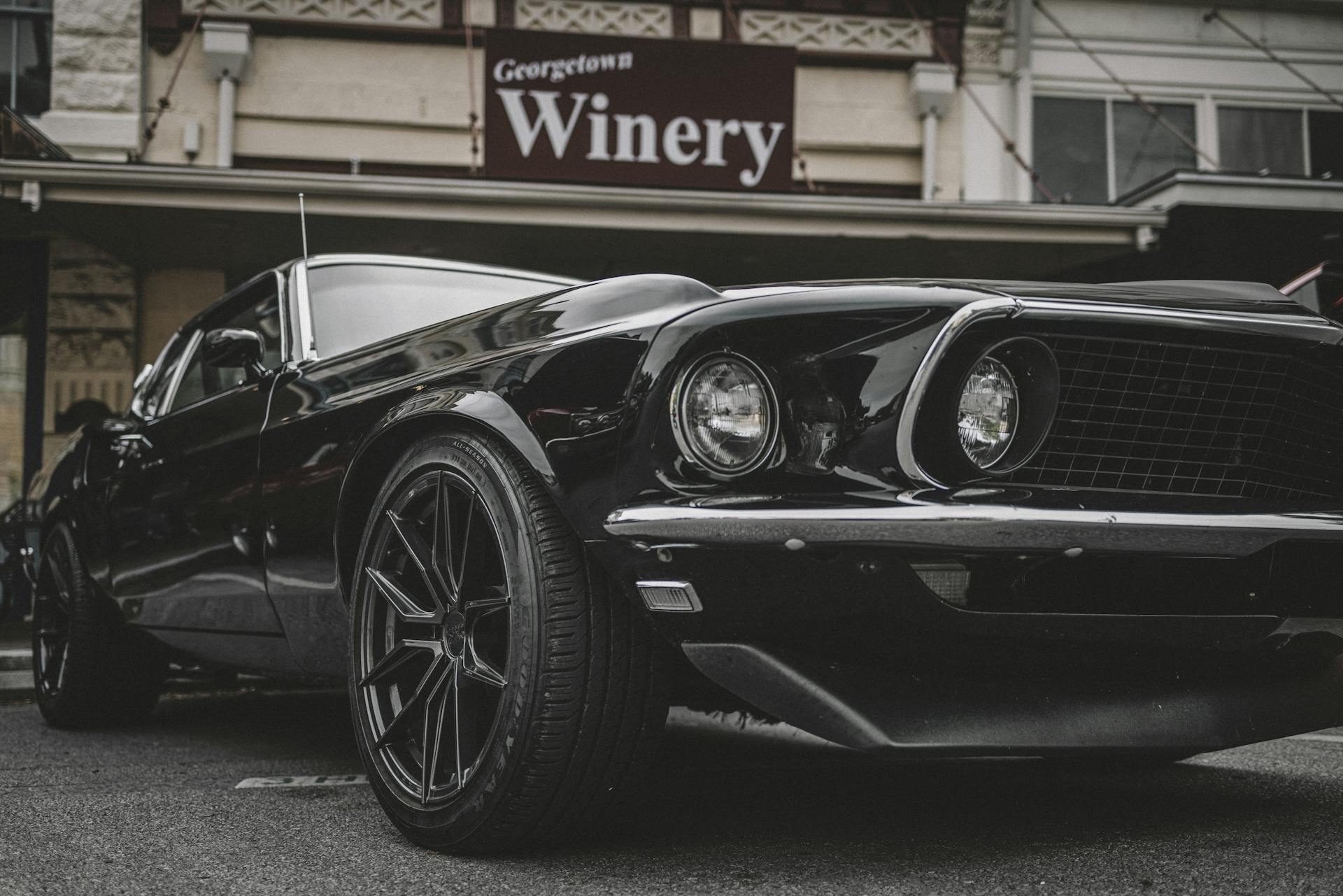 A vintage black Mustang parked outside Georgetown Winery, showcasing urban style and muscle car appeal.