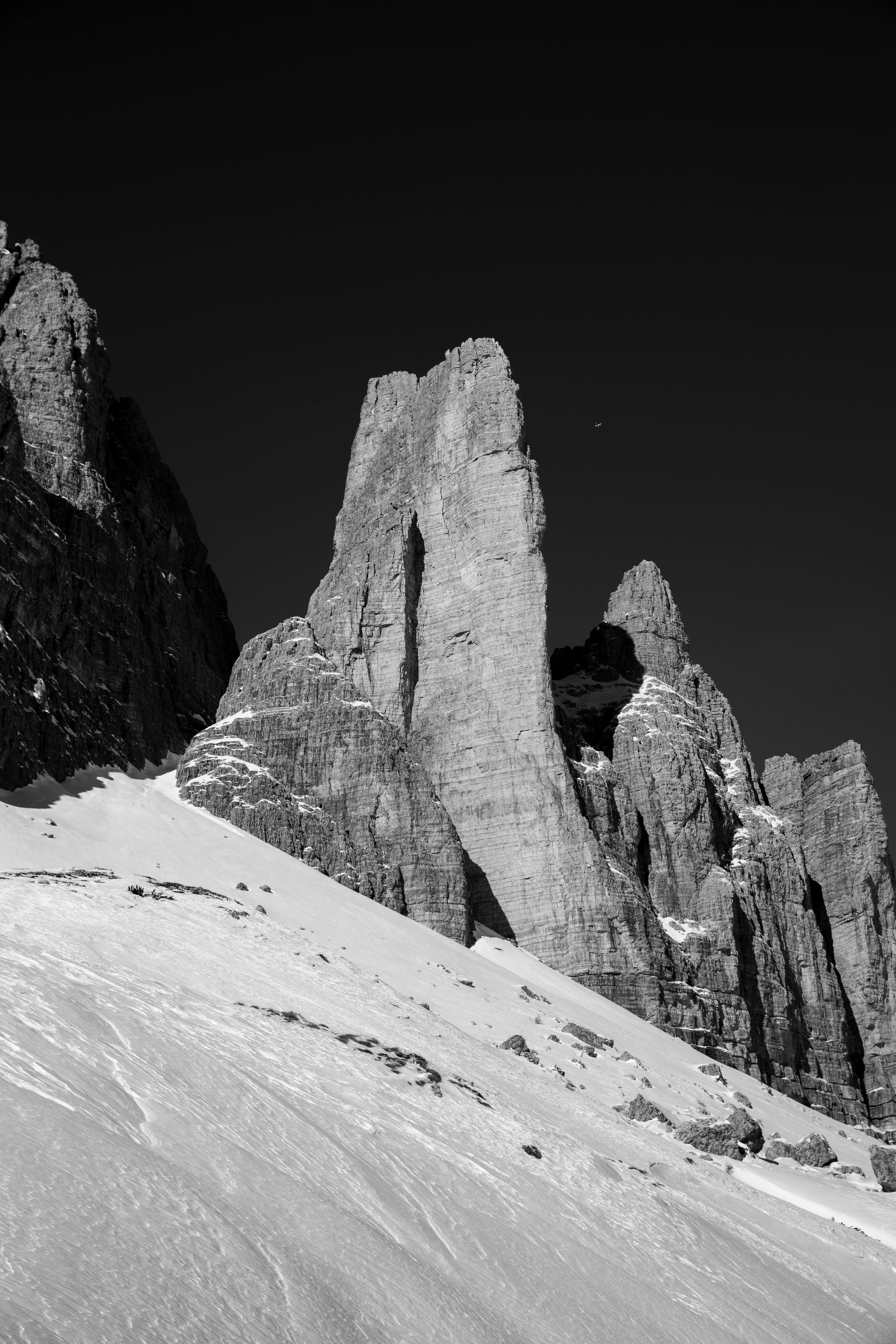 Black and white photo of snow-covered rock formations against a clear sky.