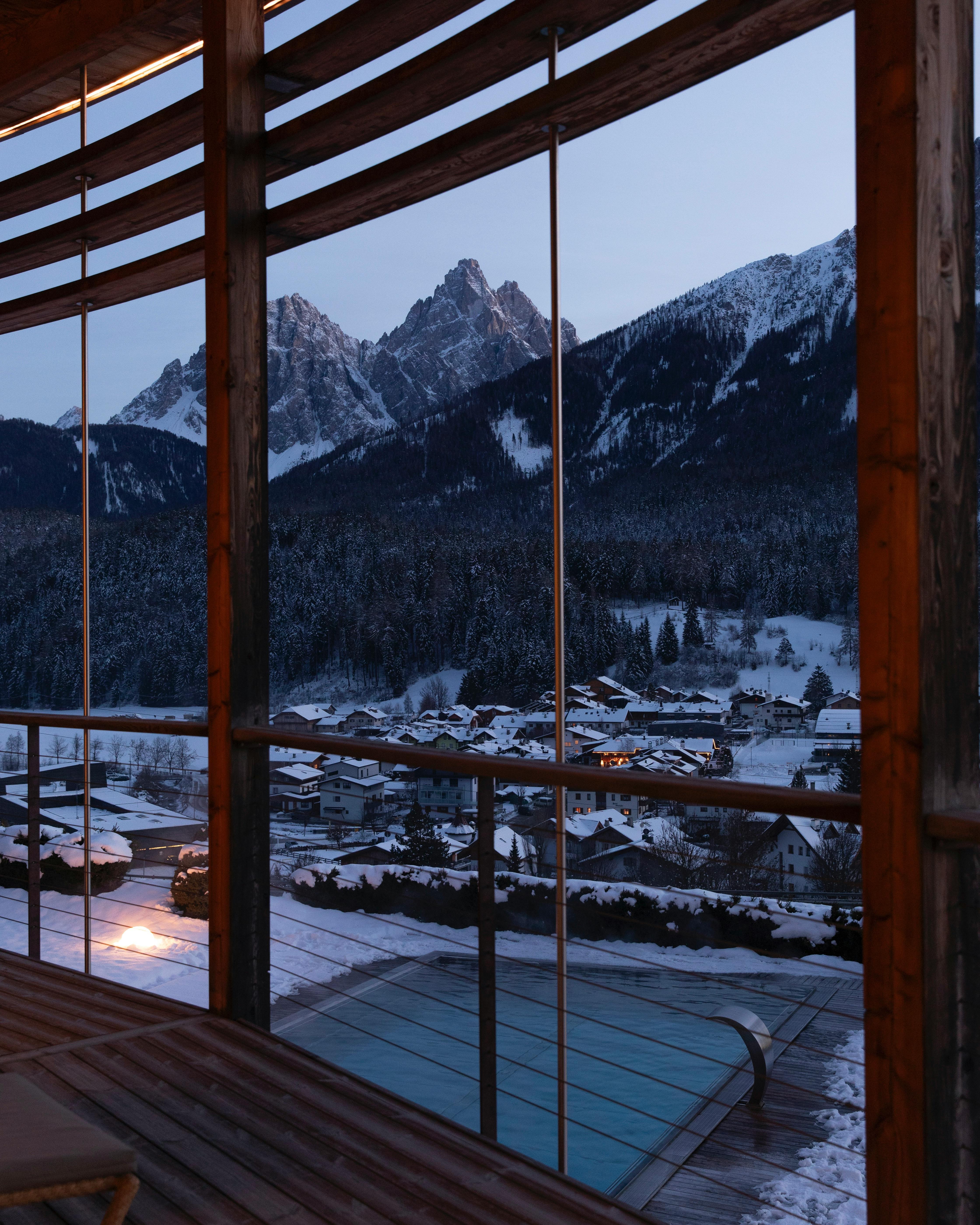 Beautiful mountain view through wooden cabin windows during winter evening.