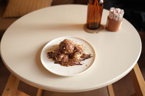 Free Delicious cream puffs drizzled with chocolate sauce, perfect dessert setting. Stock Photo
