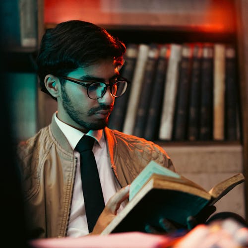 Man in Eyeglasses Sitting and Reading Book