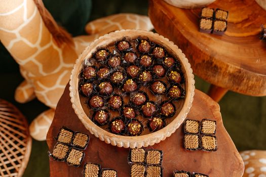 Delicious chocolate truffles with nut toppings on a wooden table, perfect for dessert lovers.