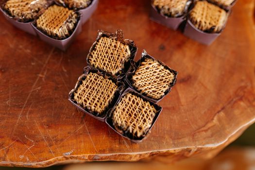 Top view of gourmet waffle chocolates in purple wrappers on a wooden platter, showcasing intricate designs.
