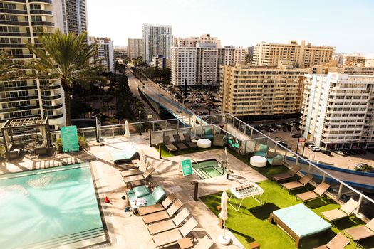 Aerial view of a luxurious rooftop pool area overlooking the vibrant downtown cityscape in Florida, USA.