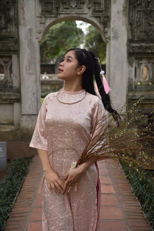 A woman in a pink dress holding a flower