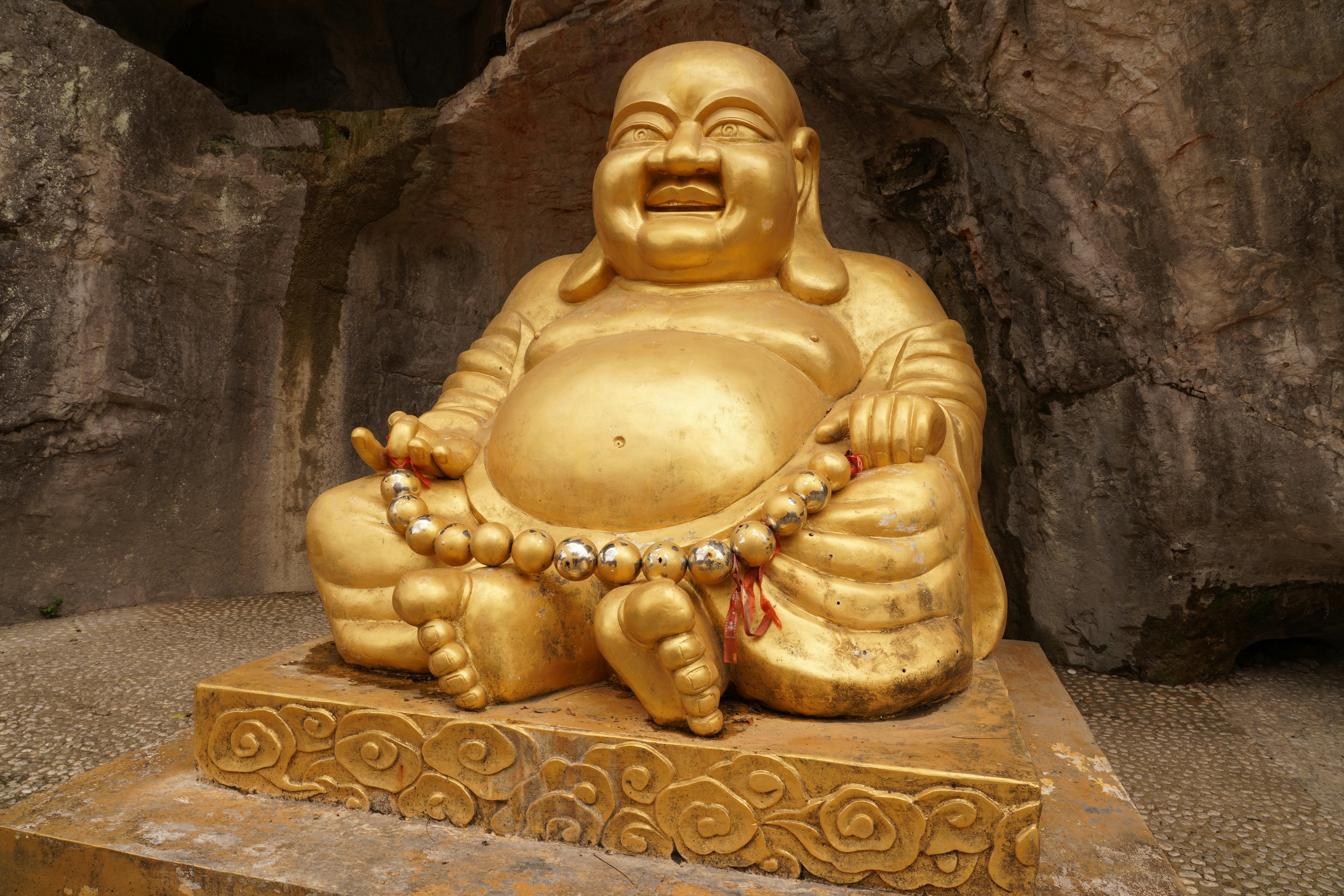 Exterior of Maha Vihara Duta Maitreya Buddhist temple in Batam Indonesia with large gold seated Buddha statue visible against blue sky