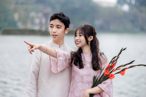 A young man and woman standing next to a lake