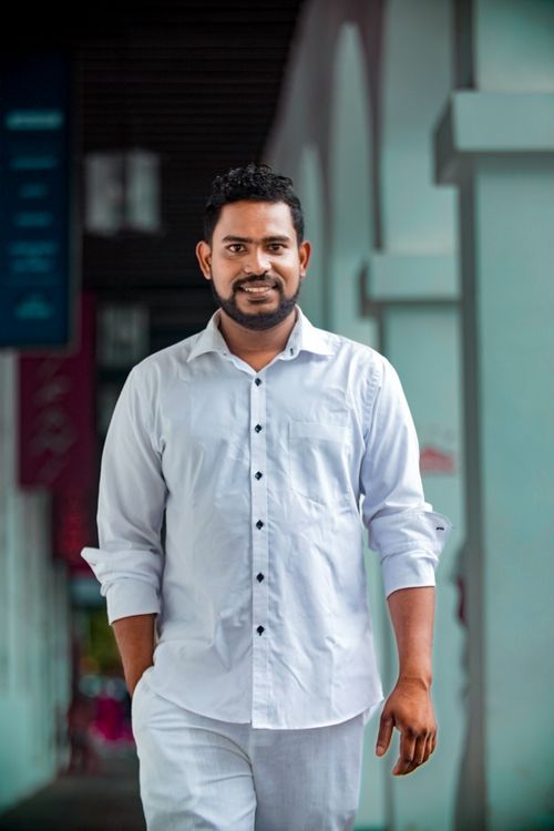 Free Portrait of a smiling man in a white shirt posing confidently outdoors. Stock Photo