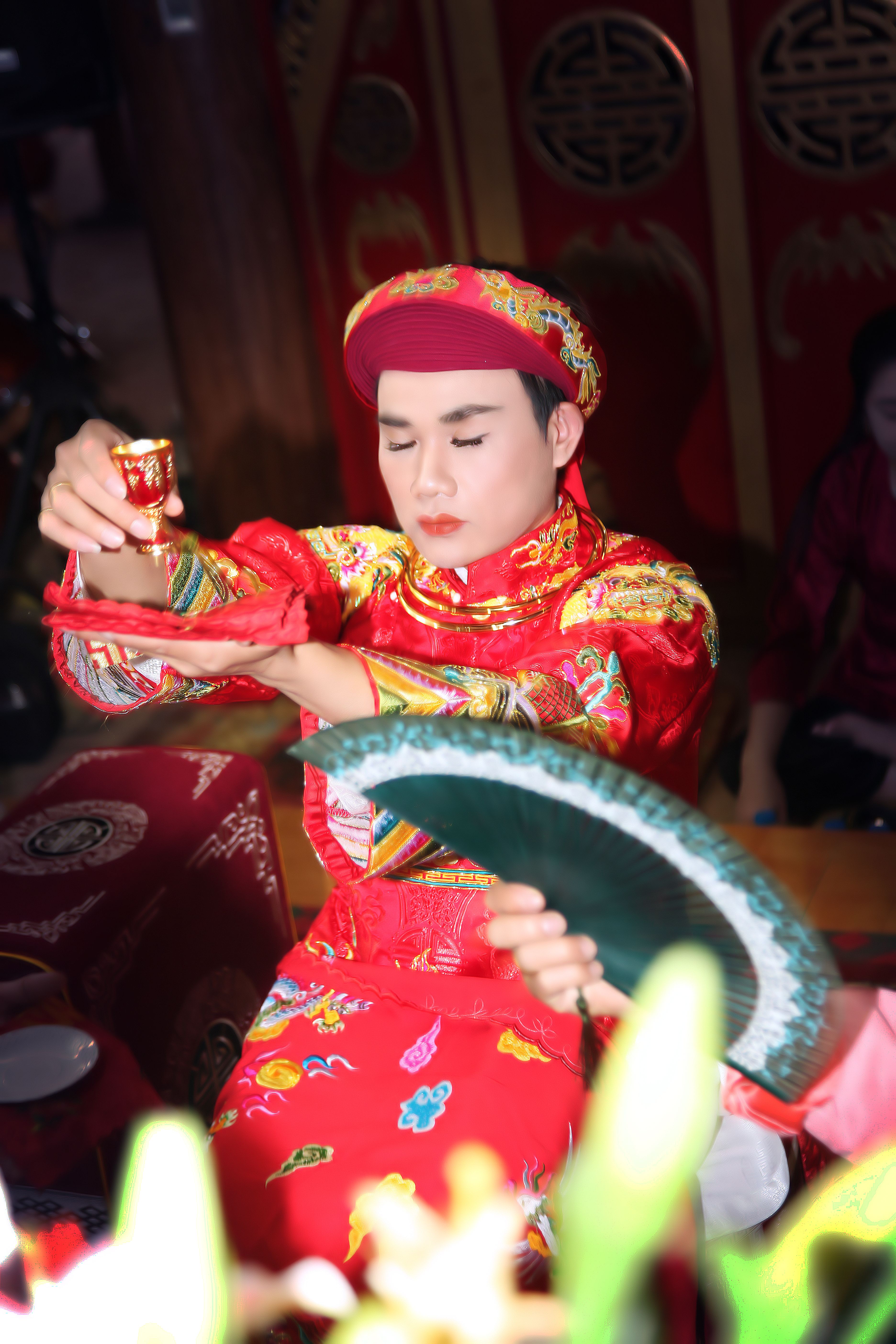 An adult performs a traditional ceremony in vibrant costume with focus on cultural attire.