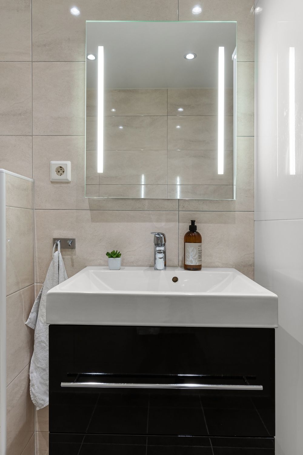 Reflets de luminaires dans un miroir au-dessus d’un lavabo de salle de bain