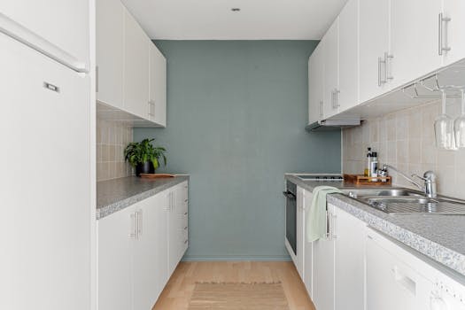 A sleek, modern kitchen with white cabinets, granite countertops, and stainless steel appliances.