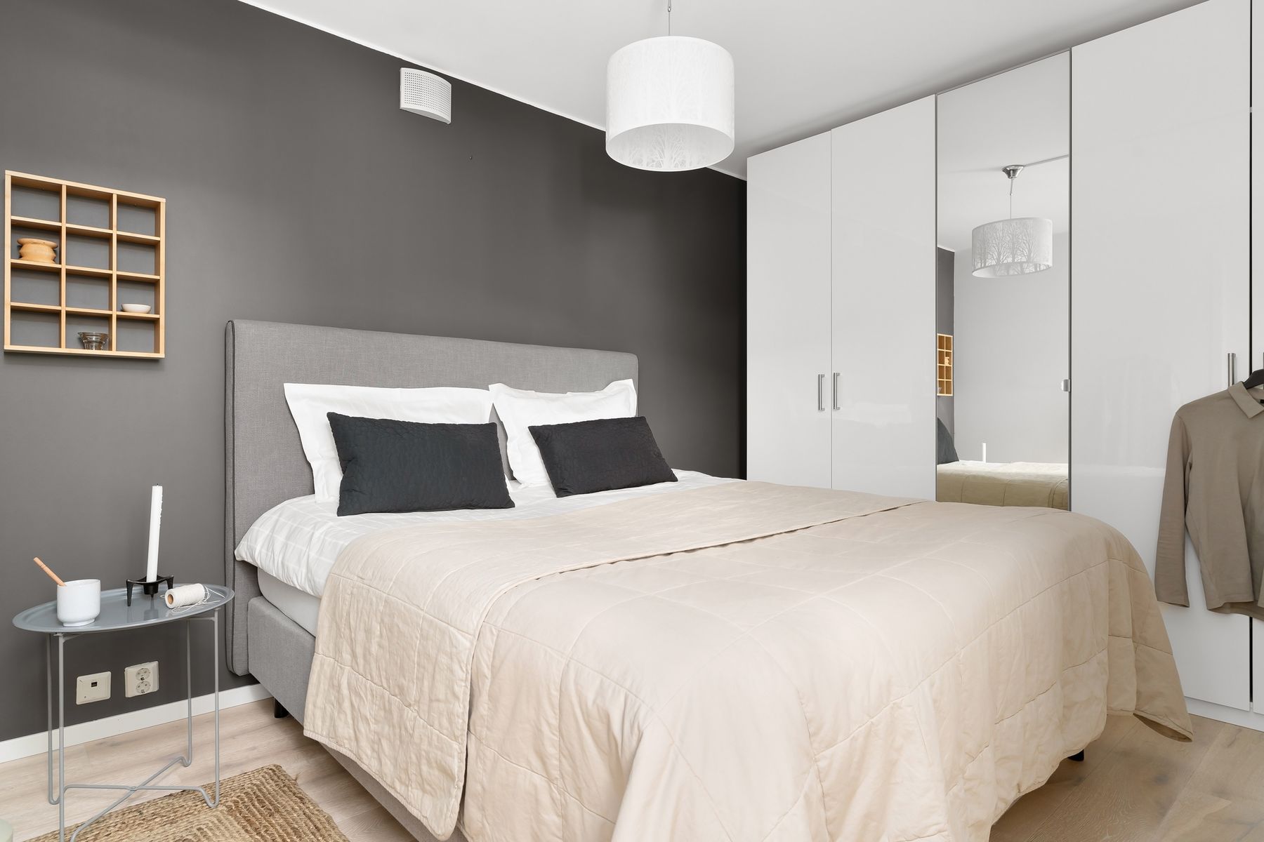Grey bedroom with a mirrored wardrobe reflecting the bed and window light