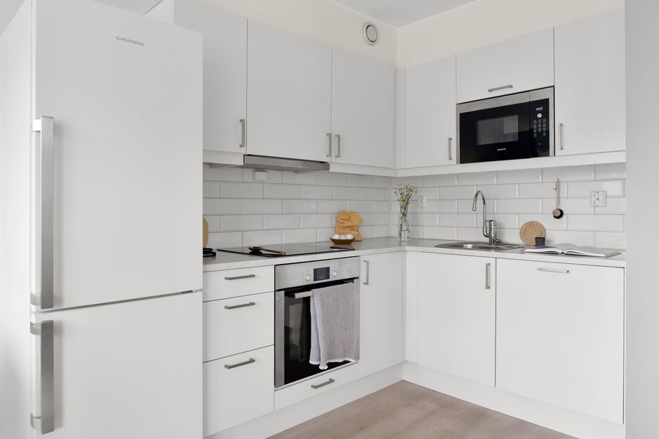 Sleek white kitchen with modern appliances and minimalist decor, perfect for elegance.