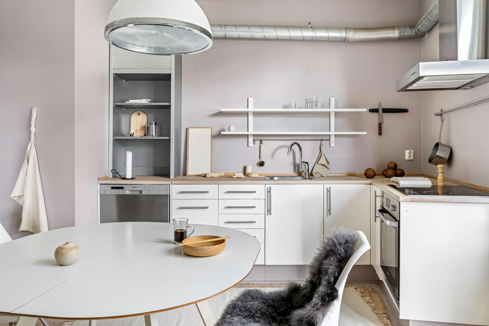 Contemporary kitchen showcasing minimalist style with white furniture and wooden accents.