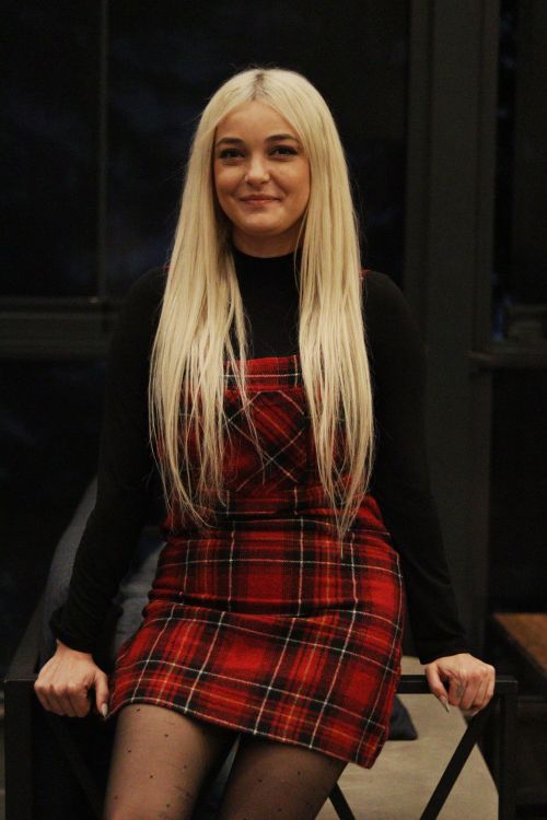 Free Fashion portrait of a woman with platinum blonde hair in a red tartan dress sitting indoors. Stock Photo