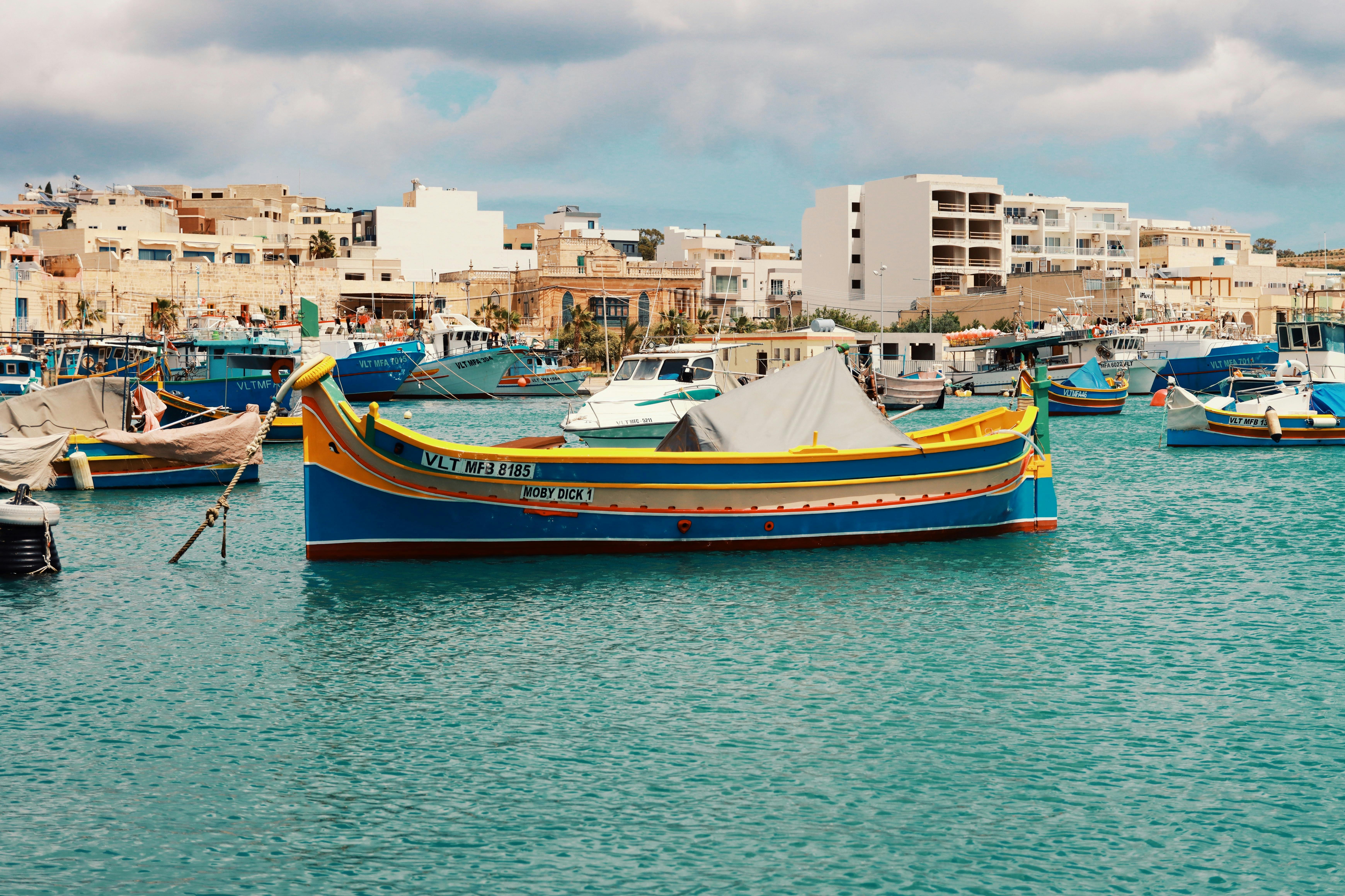 Colorful fishing boats in Marsaxlokk harbor, Malta, against a historic village backdrop.