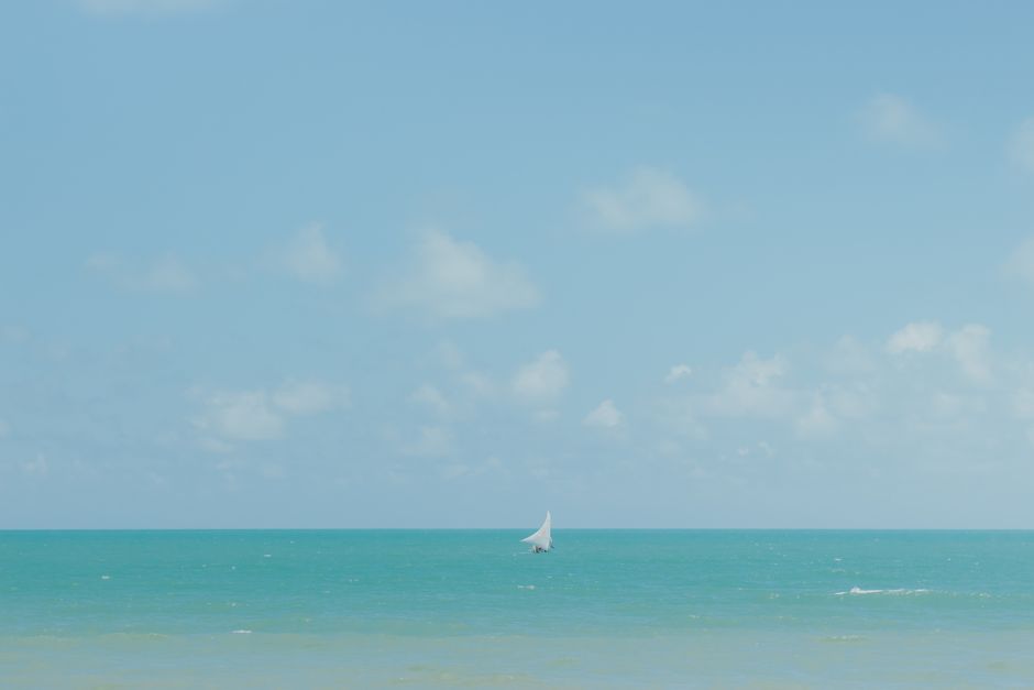 A tranquil view of a lone sailboat against the vibrant sea and sky in Majorlândia, Brazil.