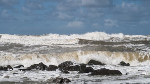 A large wave crashing into the rocks and water