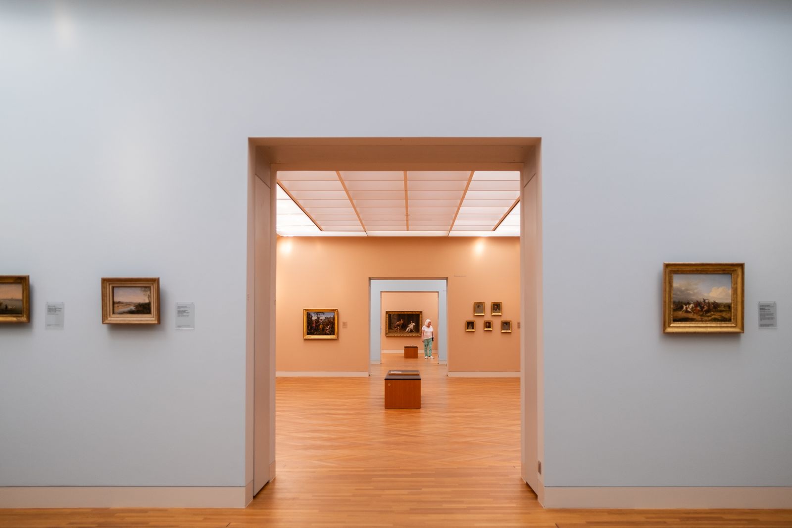 A sequence of warmly lit painting galleries seen through open doorways