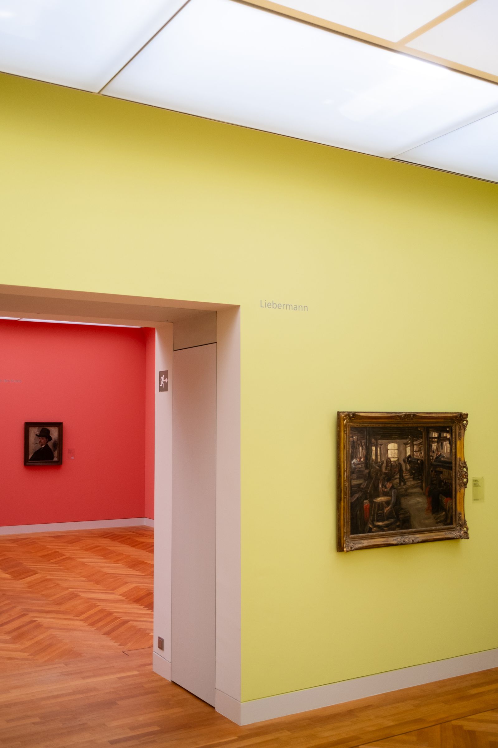 Tall, narrow museum corridor with raking daylight on textured walls