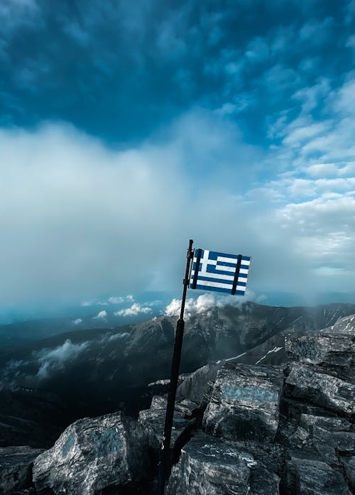 A Greek Flag on Top of a Rocky Mountain 