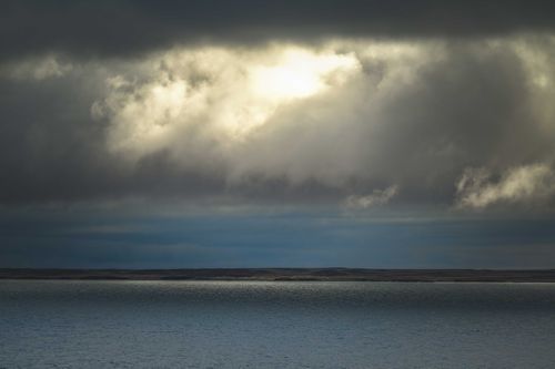 Free Dramatic clouds over a peaceful lake shore. Perfect for serene and moody landscapes. Stock Photo