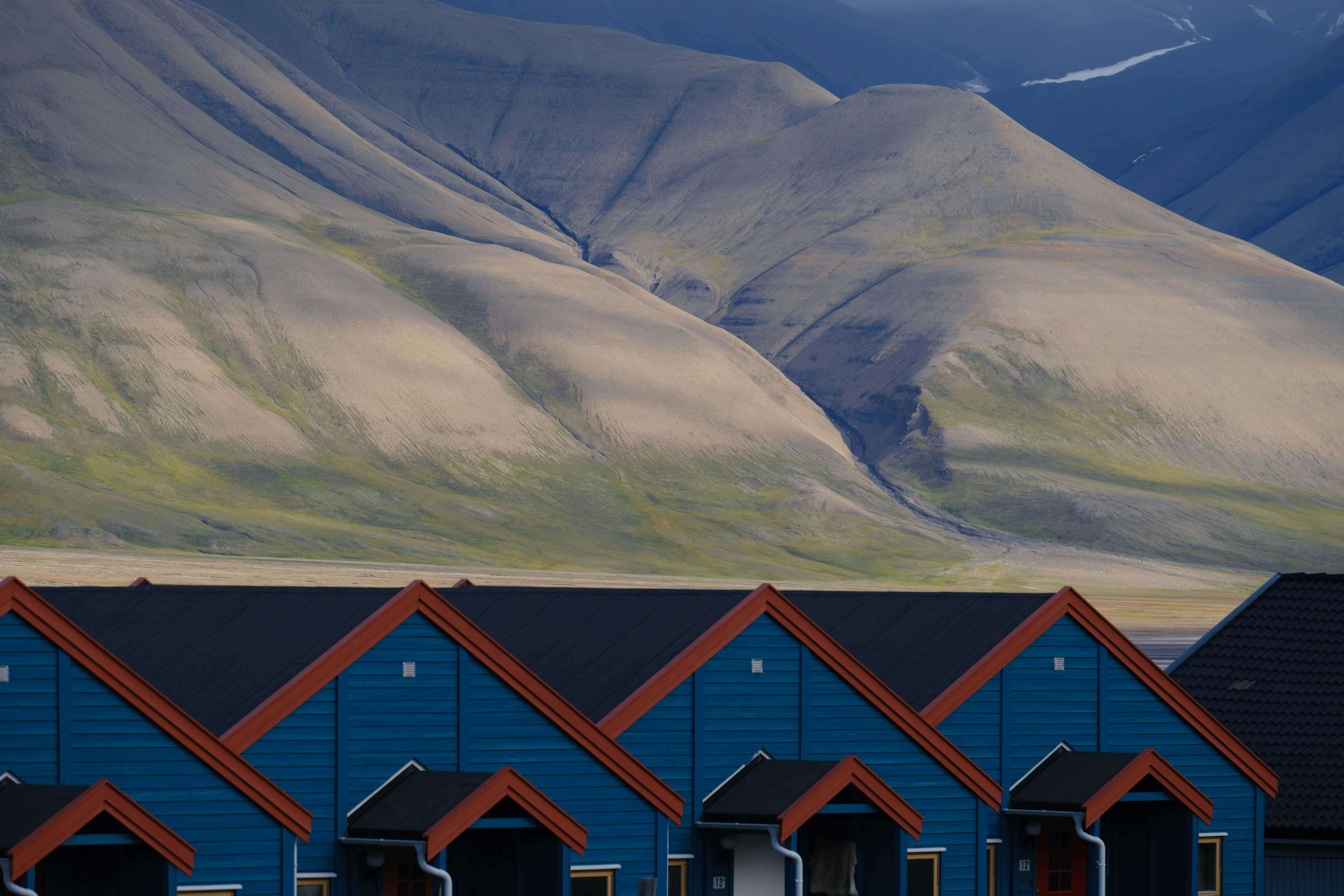 Colorful cabins in Longyearbyen, Svalbard under Arctic mountains, showcasing polar beauty.