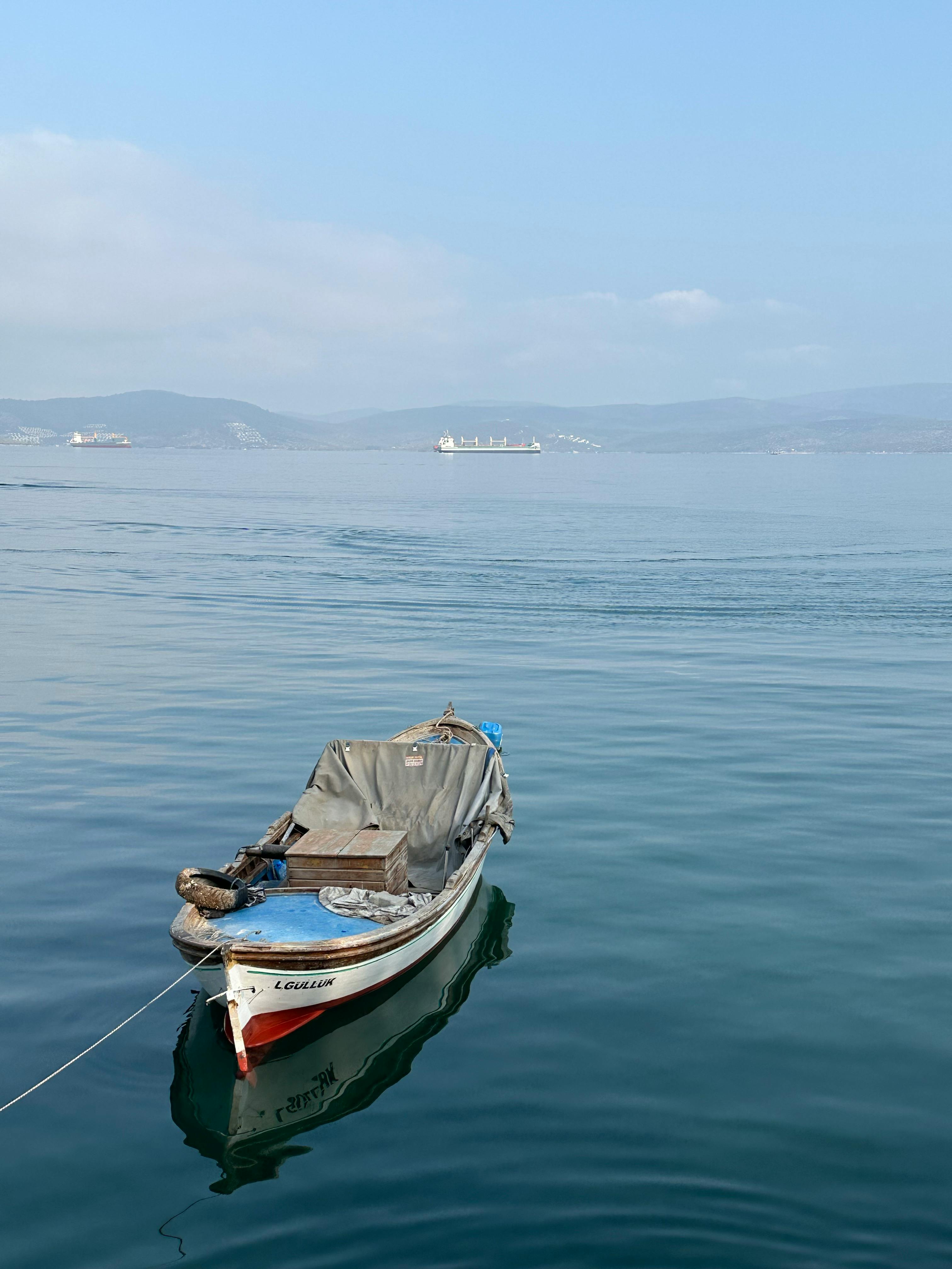 A tranquil moored boat in Bodrum, Türkiye reflecting on clear blue waters, under a calm sky.