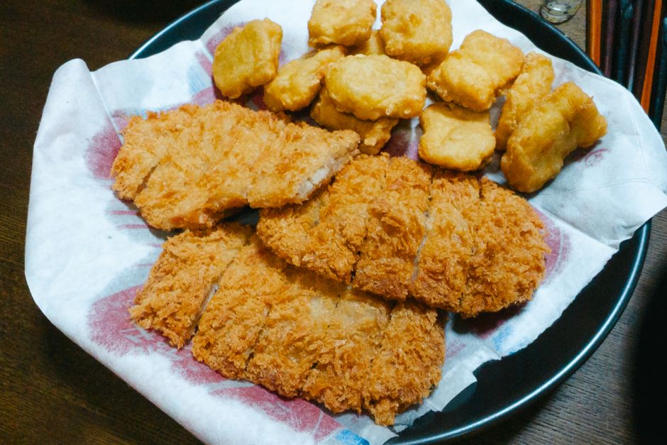Golden-brown breaded chicken nuggets and patties on white plate`