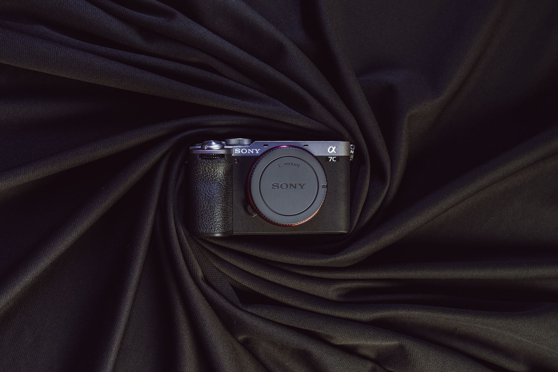 Stylish presentation of a modern mirrorless camera on elegant draped black fabric.