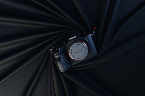 Free A Sony mirrorless camera showcased against an elegant black fabric background, highlighting modern photography technology. Stock Photo