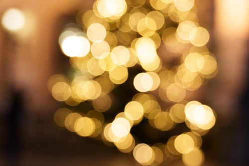 Free Blurred golden bokeh lights creating a festive, warm holiday atmosphere. Stock Photo