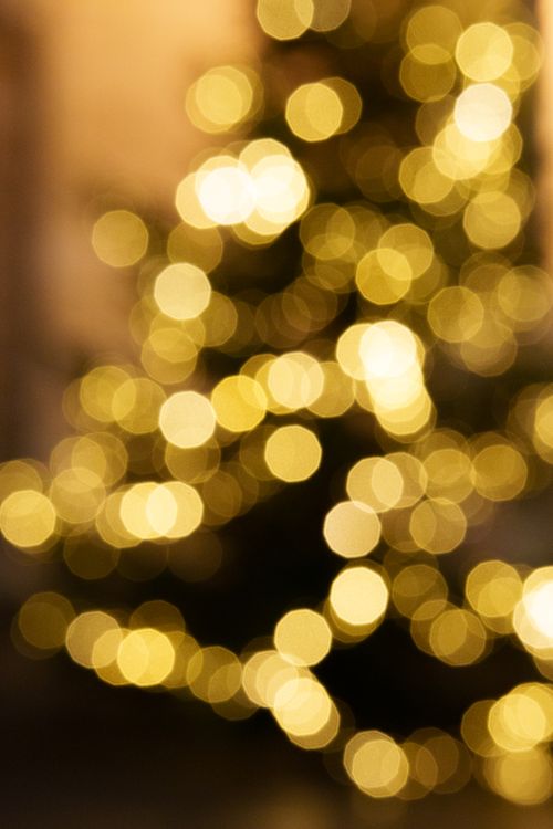 Free Bright and blurred golden bokeh lights create a festive and warm holiday ambiance. Stock Photo