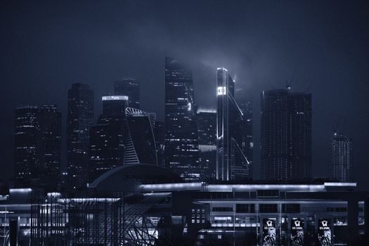 Dramatic night view of modern skyscrapers under a foggy sky.