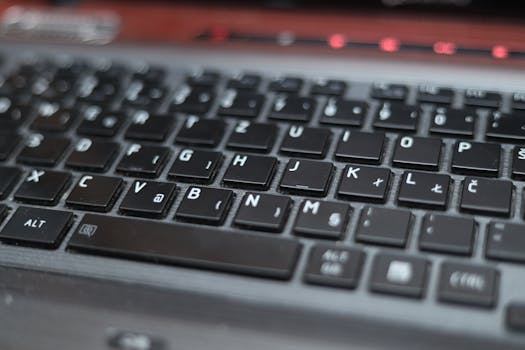 Blurred close-up of a laptop keyboard with black keys and symbols, highlighting technology.