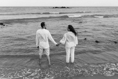 Couple in White Stand in Sea and Hold Hands
