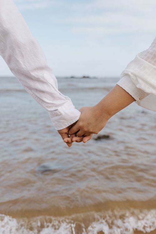 Free A couple holding hands by the seaside, showcasing love and connection. Stock Photo