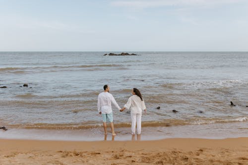 Back View of a Couple Holding Hands on a Beach 