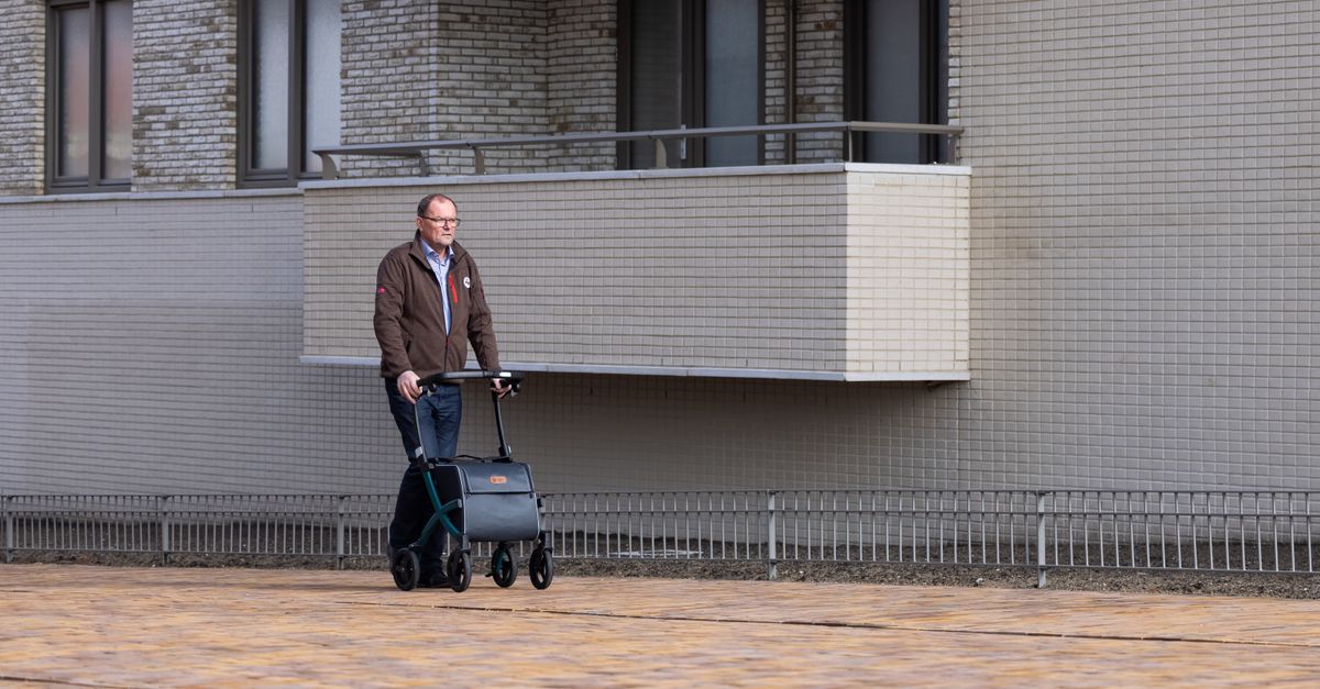 Elderly man using a rollator on urban street, outdoor setting in daylight.